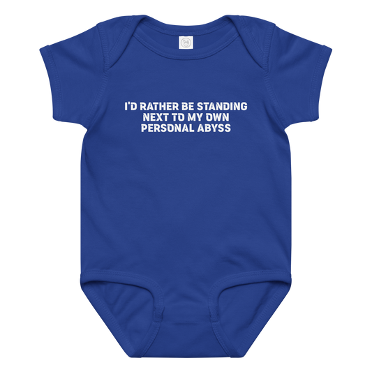 "I'd rather be standing next to my own personal abyss" printed on a royal baby jersey bodysuit laying on a flat surface amongst other clothes