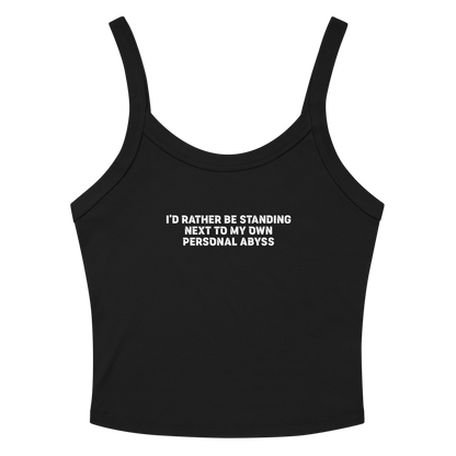 "I'd rather be standing next to my own personal abyss" printed on a solid black blend women's micro-rib tanktop laying on a flat surface amongst sunglasses and shorts