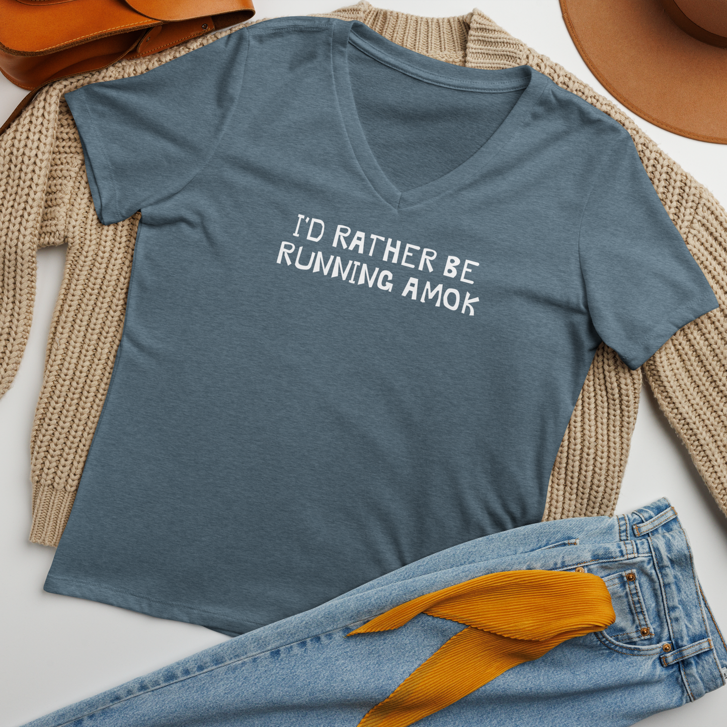 "I’d rather be running amok" printed on a heather slate women's relaxed v-neck t-shirt laying on a flat surface amongst other clothes