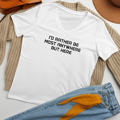 "I’d rather be most anywhere but here" printed on a solid white blend women's relaxed v-neck t-shirt laying on a flat surface amongst other clothes