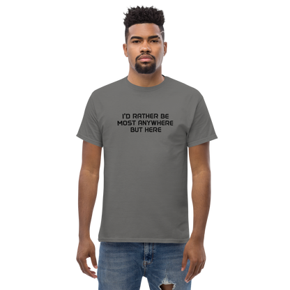 "I’d rather be most anywhere but here" printed on a charcoal unisex classic tee worn by a male