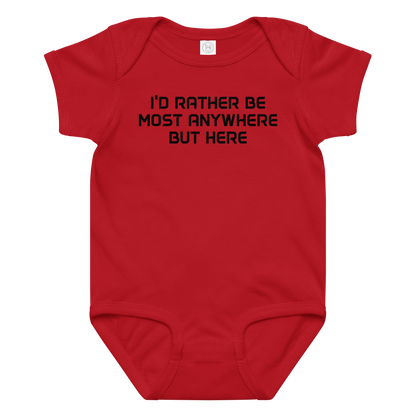 "I’d rather be most anywhere but here" printed on a red baby jersey bodysuit laying on a flat surface amongst other clothes