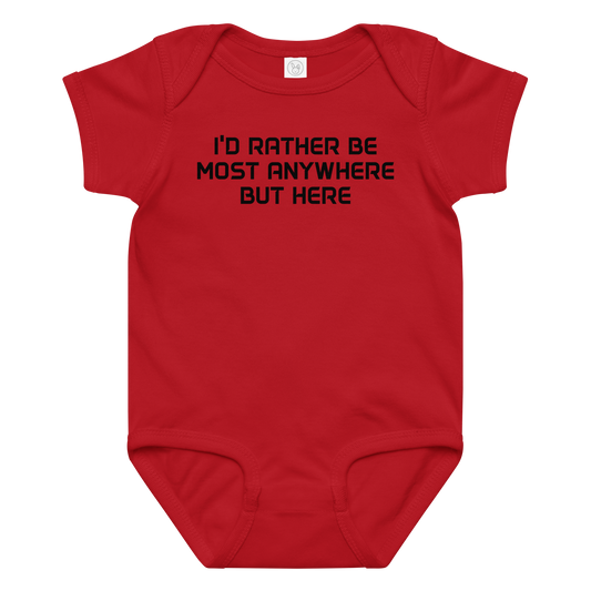 "I’d rather be most anywhere but here" printed on a red baby jersey bodysuit laying on a flat surface amongst other clothes