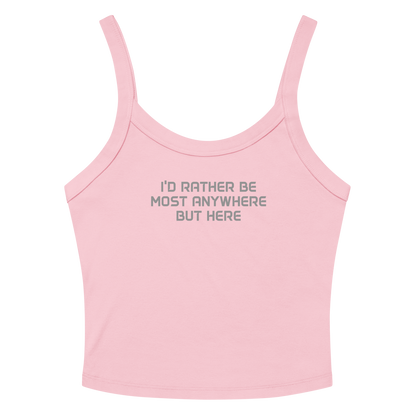 "I’d rather be most anywhere but here" printed on a solid pink blend women's micro-rib tanktop laying on a flat surface amongst sunglasses and shorts