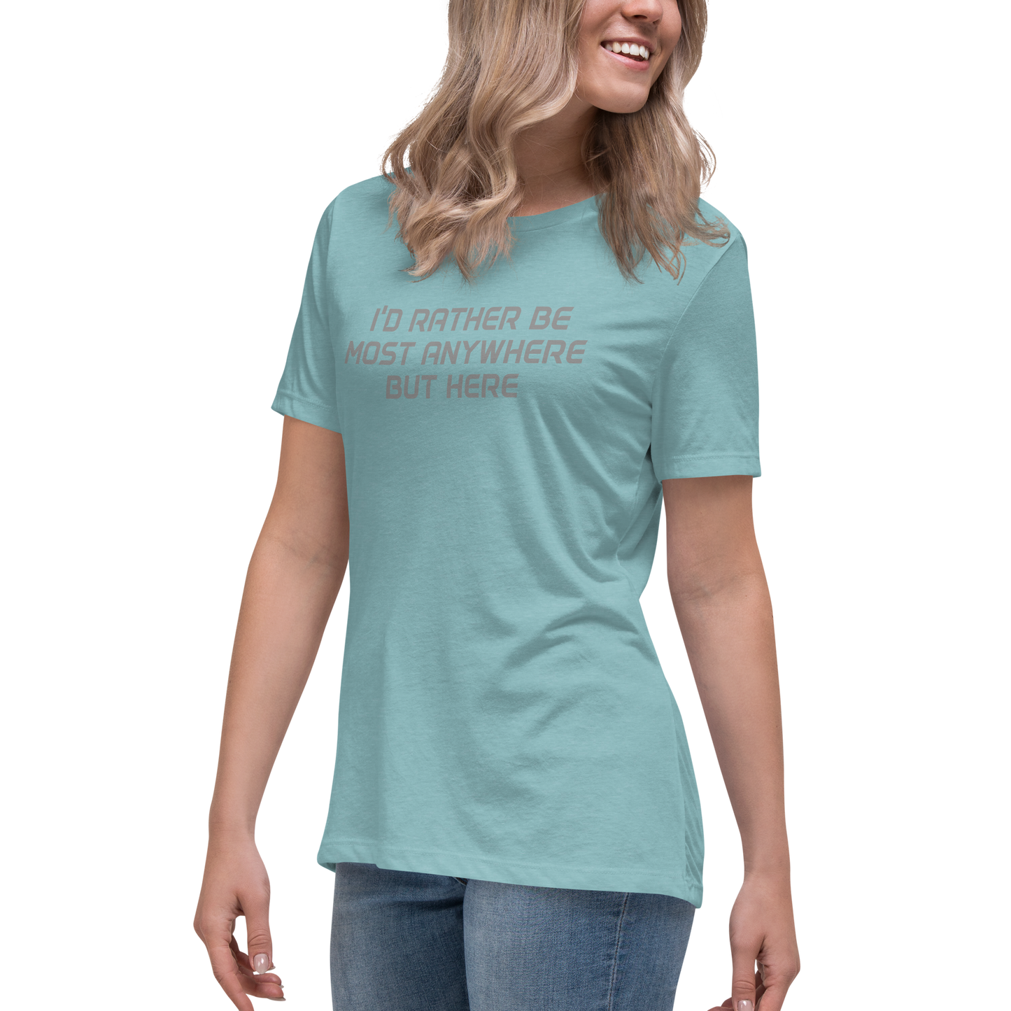 "I’d rather be most anywhere but here" printed on a heather blue lagoon women's relaxed t-shirt worn by a female