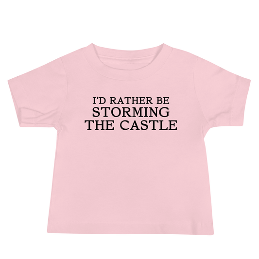 "I'd rather be storming the castle" printed on a pink baby jersey short sleeve tee laying on a flat surface
