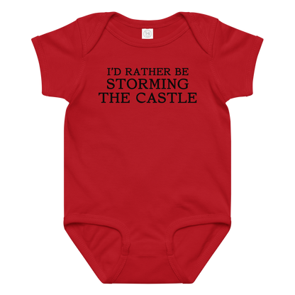 "I'd rather be storming the castle" printed on a red baby jersey bodysuit laying on a flat surface amongst other clothes