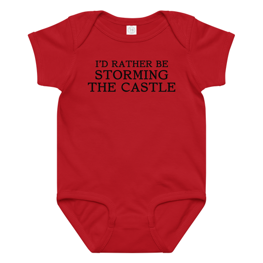 "I'd rather be storming the castle" printed on a red baby jersey bodysuit laying on a flat surface amongst other clothes