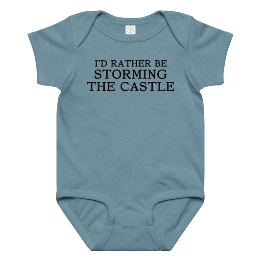 "I'd rather be storming the castle" printed on a vintage indigo baby jersey bodysuit laying on a flat surface amongst other clothes