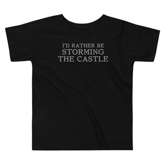 "I'd rather be storming the castle" printed on a black toddler short sleeve tee laying on a flat surface