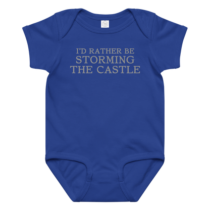 "I'd rather be storming the castle" printed on a royal baby jersey bodysuit laying on a flat surface amongst other clothes