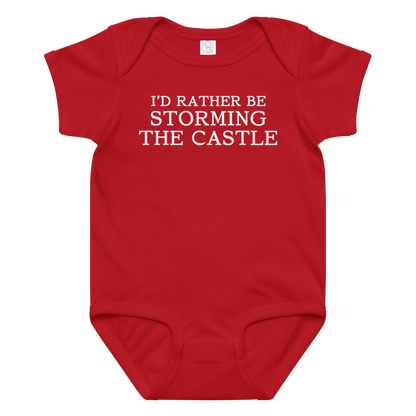 "I'd rather be storming the castle" printed on a red baby jersey bodysuit laying on a flat surface amongst other clothes