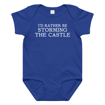 "I'd rather be storming the castle" printed on a royal baby jersey bodysuit laying on a flat surface amongst other clothes