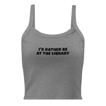"I’d rather be at the library" printed on a athletic heather women's micro-rib tanktop laying on a flat surface