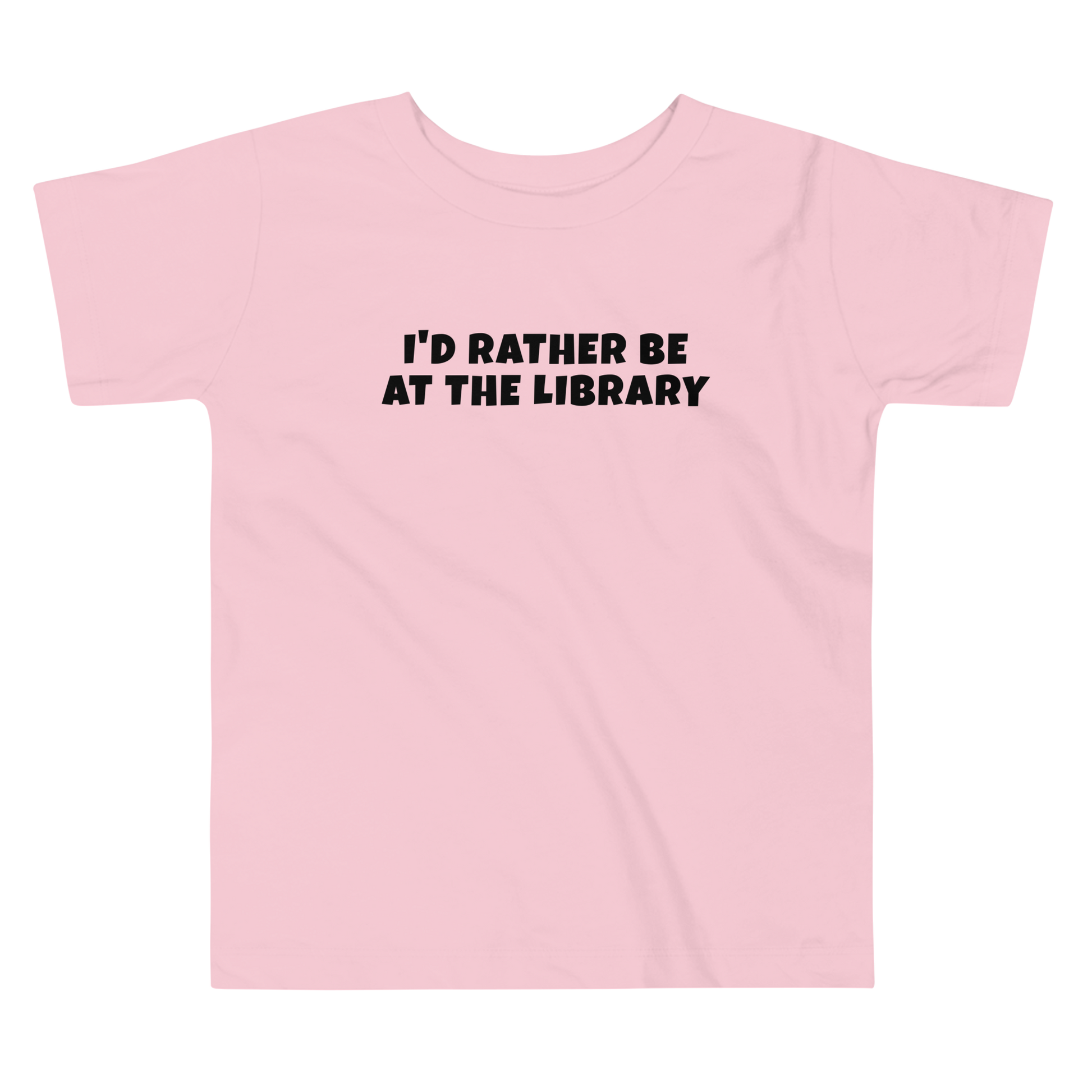 "I’d rather be at the library" printed on a pink toddler short sleeve tee laying on a flat surface