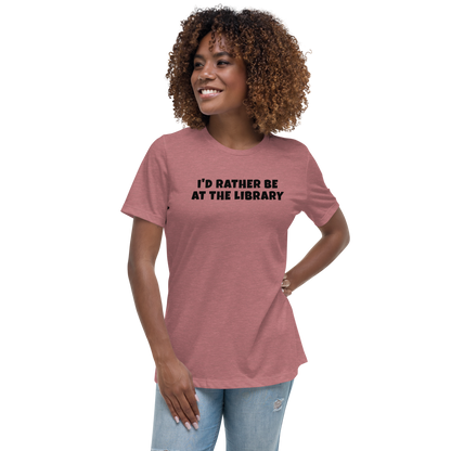 "I’d rather be at the library" printed on a heather mauve women's relaxed t-shirt worn by a female
