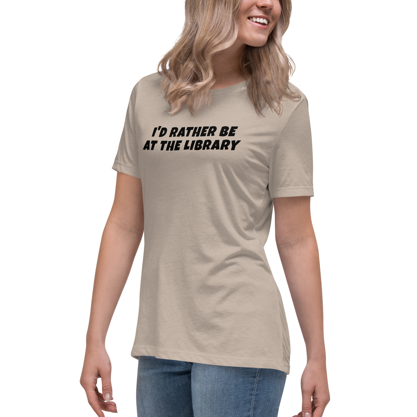 "I’d rather be at the library" printed on a heather stone women's relaxed t-shirt worn by a female