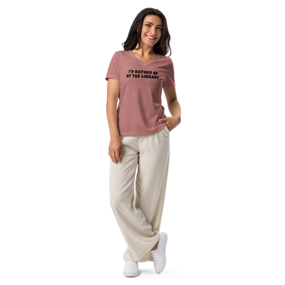 "I’d rather be at the library" printed on a heather mauve women's relaxed v-neck t-shirt worn by a female