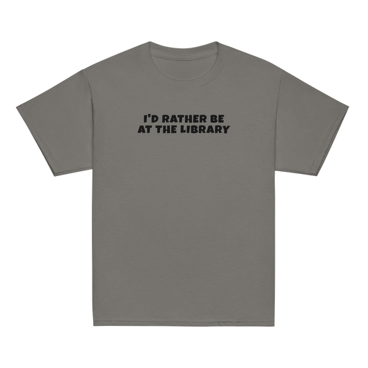 "I’d rather be at the library" printed on a charcoal youth classic tee laying on a flat surface