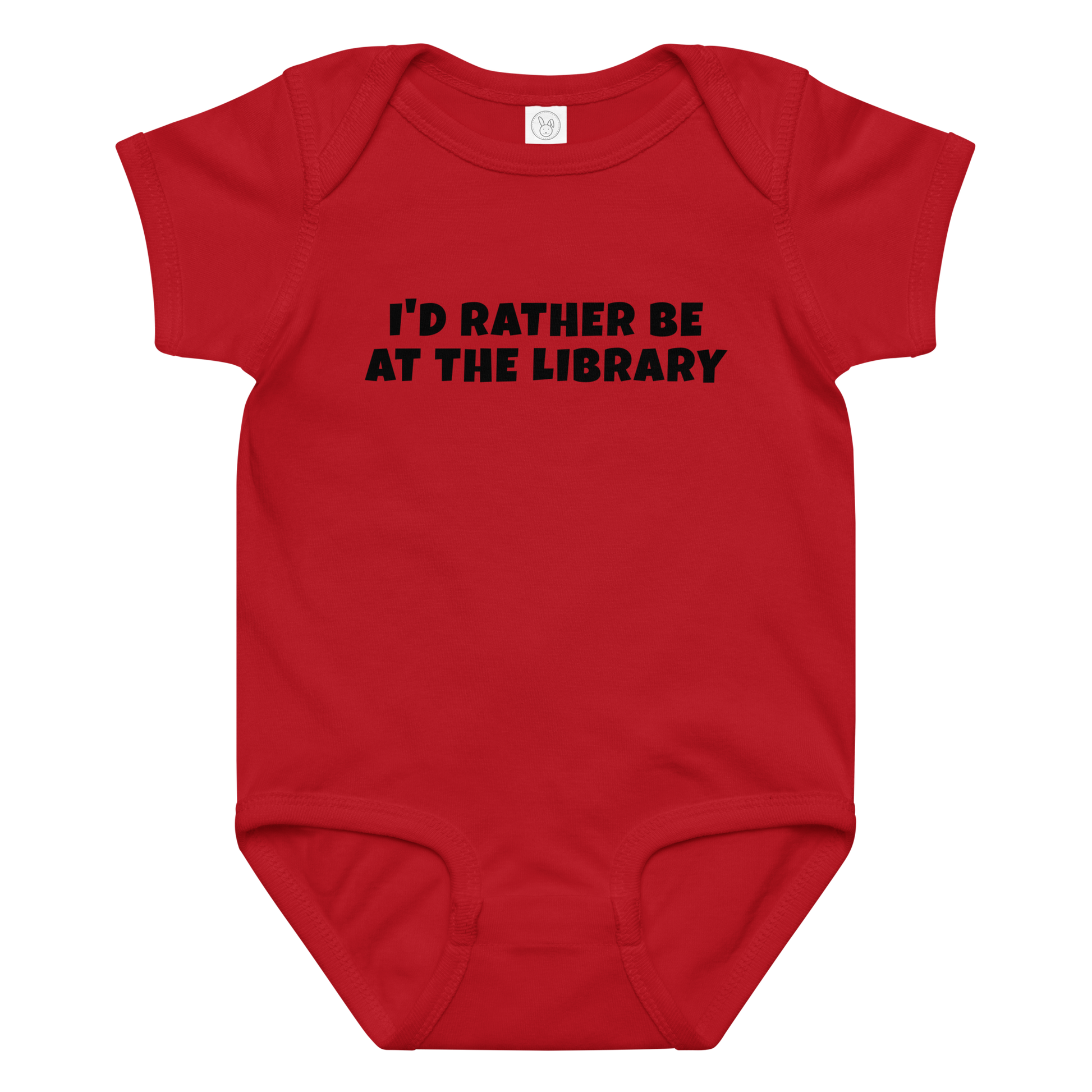 "I’d rather be at the library" printed on a red baby jersey bodysuit laying on a flat surface amongst other clothes