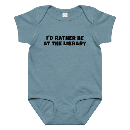 "I’d rather be at the library" printed on a vintage indigo baby jersey bodysuit laying on a flat surface amongst other clothes