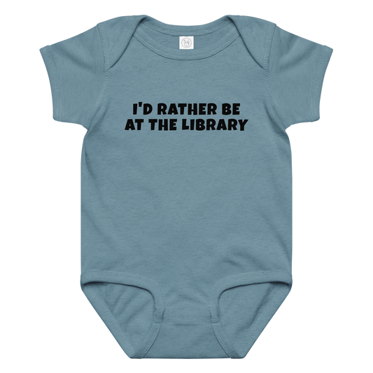 "I’d rather be at the library" printed on a vintage indigo baby jersey bodysuit laying on a flat surface amongst other clothes