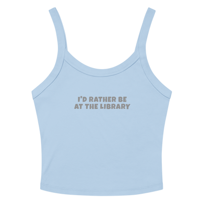 "I’d rather be at the library" printed on a solid baby blue blend women's micro-rib tanktop laying on a flat surface amongst sunglasses and shorts