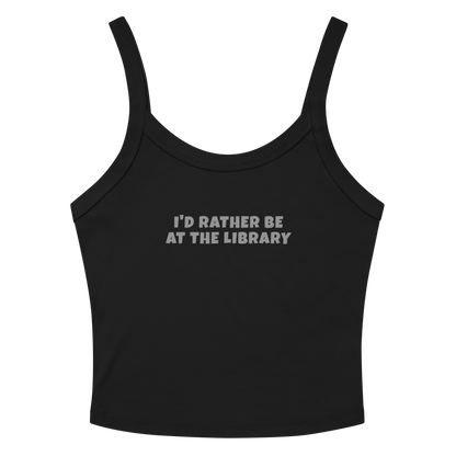 "I’d rather be at the library" printed on a solid black blend women's micro-rib tanktop laying on a flat surface amongst sunglasses and shorts