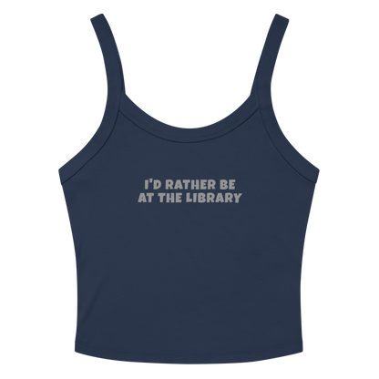 "I’d rather be at the library" printed on a solid navy blend women's micro-rib tanktop laying on a flat surface amongst sunglasses and shorts