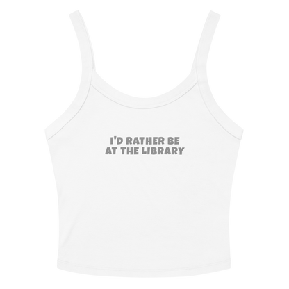 "I’d rather be at the library" printed on a solid white blend women's micro-rib tanktop laying on a flat surface amongst sunglasses and shorts