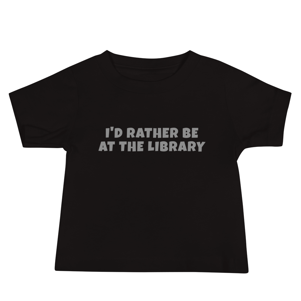 "I’d rather be at the library" printed on a black baby jersey short sleeve tee laying on a flat surface
