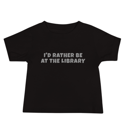 "I’d rather be at the library" printed on a black baby jersey short sleeve tee laying on a flat surface