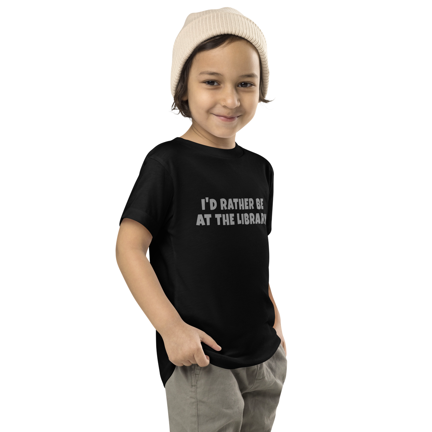 "I’d rather be at the library" printed on a black toddler short sleeve tee worn by a male who is also wearing a knit cap
