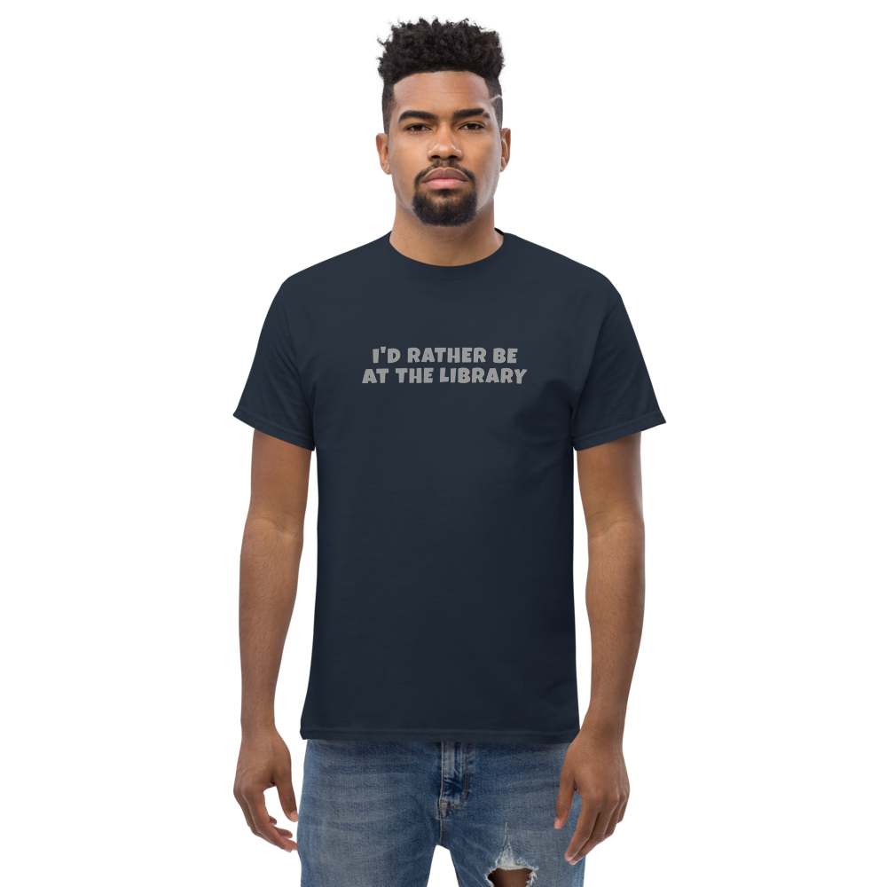 "I’d rather be at the library" printed on a navy unisex classic tee worn by a male