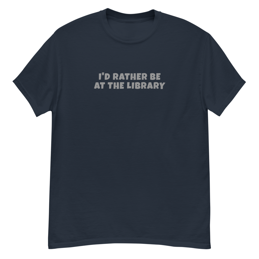 "I’d rather be at the library" printed on a navy unisex classic tee laying on a flat surface