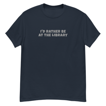"I’d rather be at the library" printed on a navy unisex classic tee laying on a flat surface