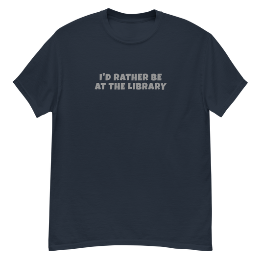 "I’d rather be at the library" printed on a navy unisex classic tee laying on a flat surface