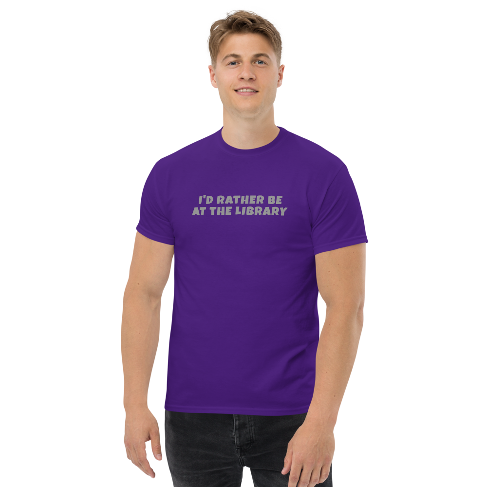 "I’d rather be at the library" printed on a purple unisex classic tee worn by a male