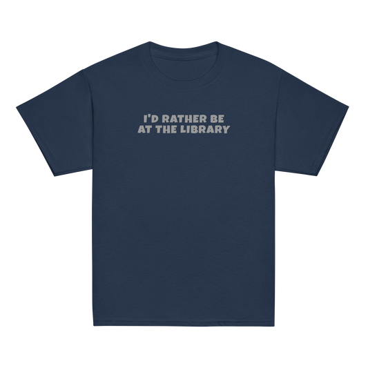 "I’d rather be at the library" printed on a navy youth classic tee laying on a flat surface