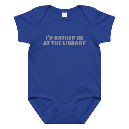 "I’d rather be at the library" printed on a royal baby jersey bodysuit laying on a flat surface amongst other clothes