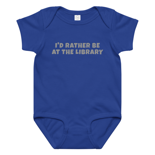 "I’d rather be at the library" printed on a royal baby jersey bodysuit laying on a flat surface amongst other clothes