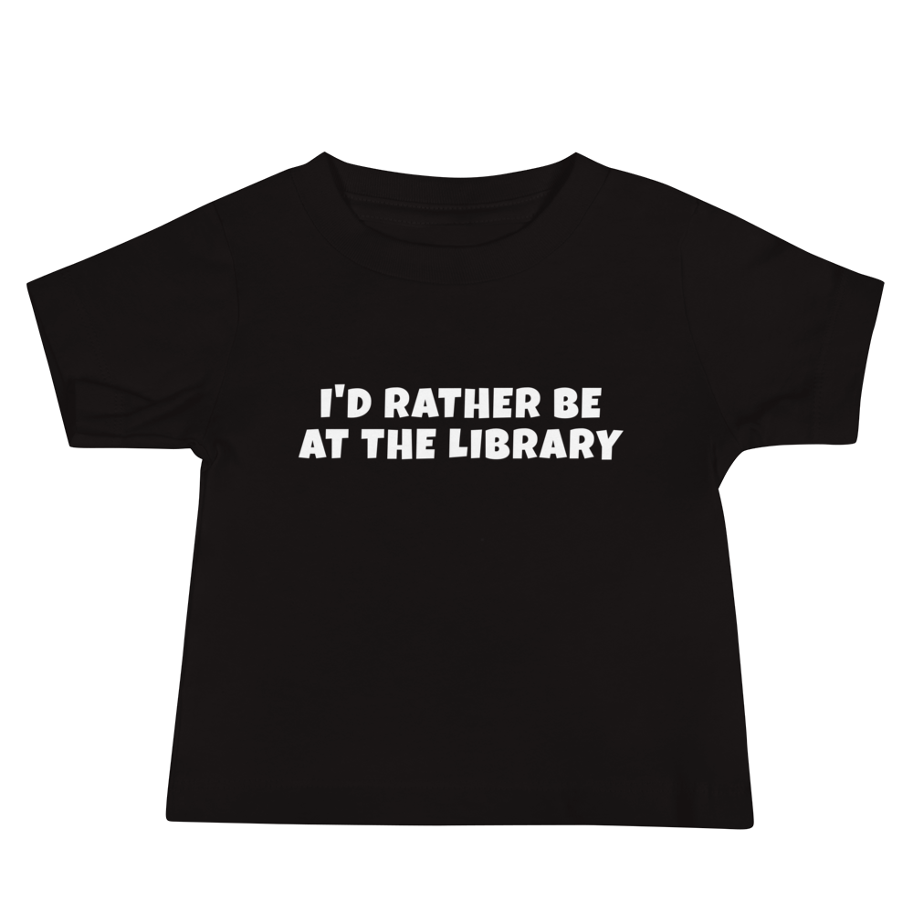 "I’d rather be at the library" printed on a black baby jersey short sleeve tee laying on a flat surface