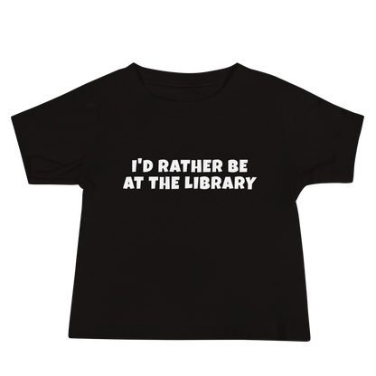 "I’d rather be at the library" printed on a black baby jersey short sleeve tee laying on a flat surface