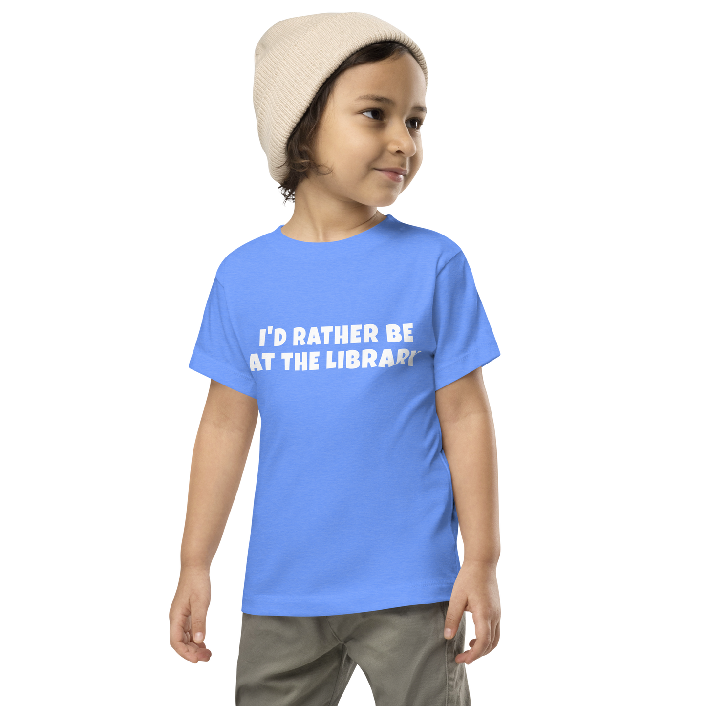 "I’d rather be at the library" printed on a heather columbia blue toddler short sleeve tee worn by a male wearing a cap