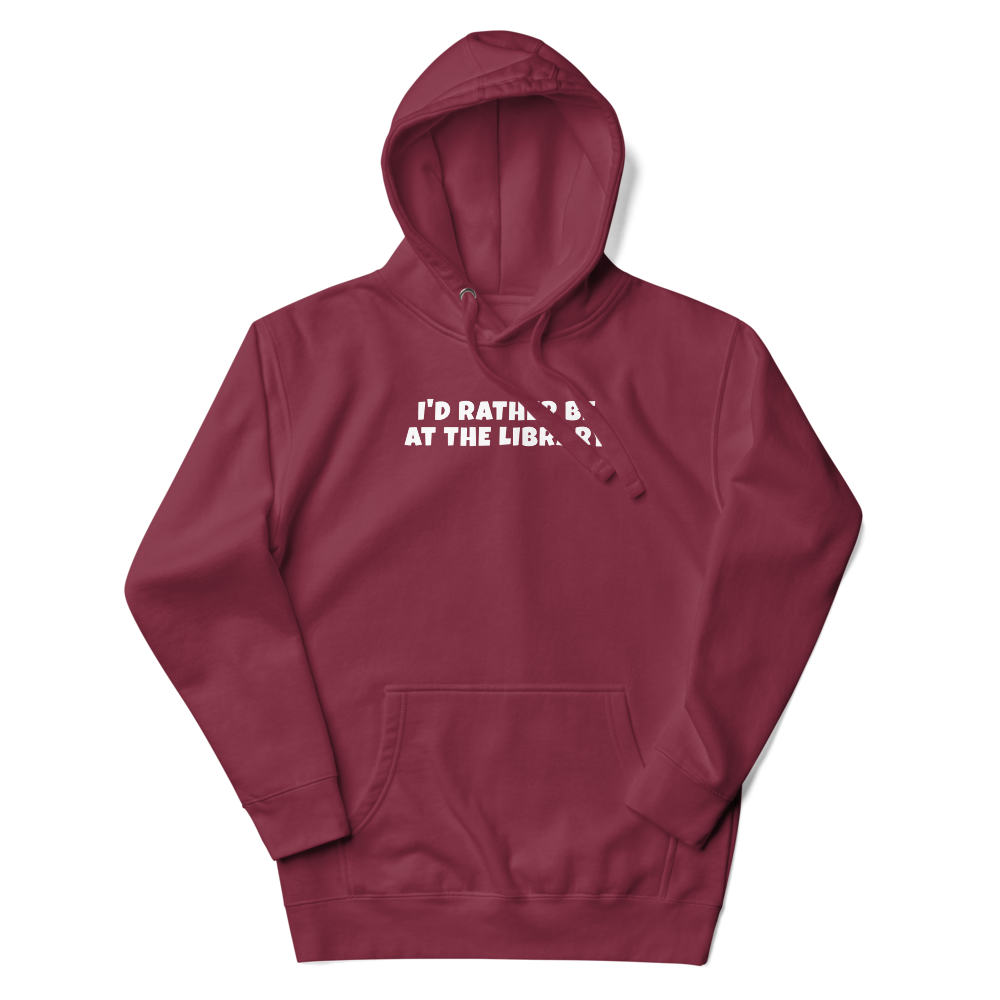 "I’d rather be at the library" printed on a maroon unisex hoodie laying on a flat surface with the hood up