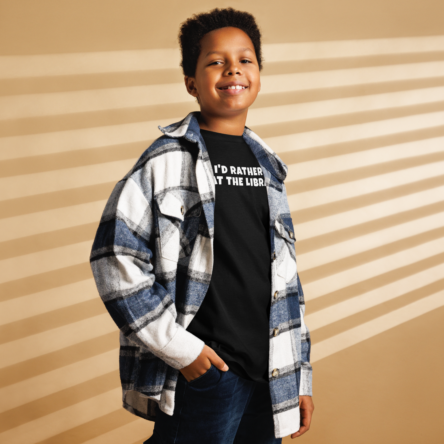 "I’d rather be at the library" printed on a black youth classic tee worn by a male also wearing a jacket