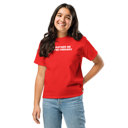 "I’d rather be at the library" printed on a red youth classic tee worn by a female