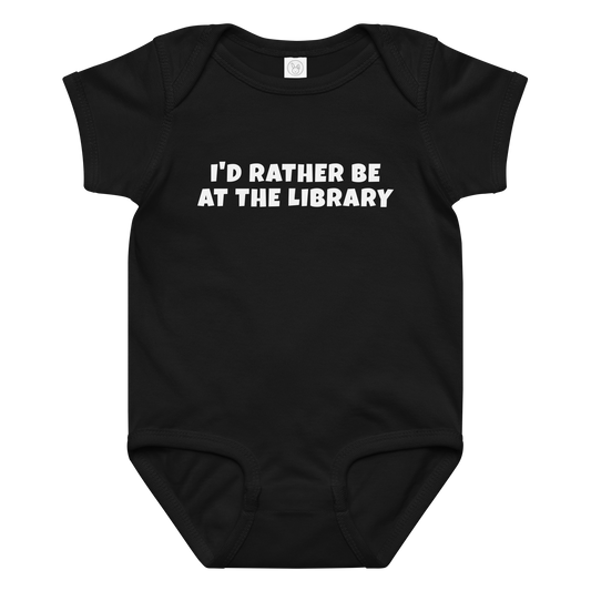 "I’d rather be at the library" printed on a black baby jersey bodysuit laying on a flat surface amongst other clothes