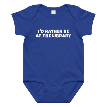 "I’d rather be at the library" printed on a royal baby jersey bodysuit laying on a flat surface amongst other clothes
