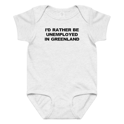 "I'd rather be unemployed in greenland" printed on a ash baby jersey bodysuit laying on a flat surface amongst other clothes